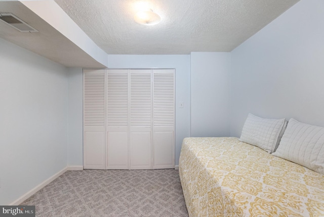 carpeted bedroom featuring a closet and a textured ceiling