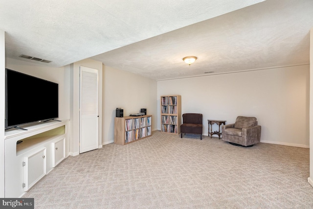 sitting room with light colored carpet and a textured ceiling