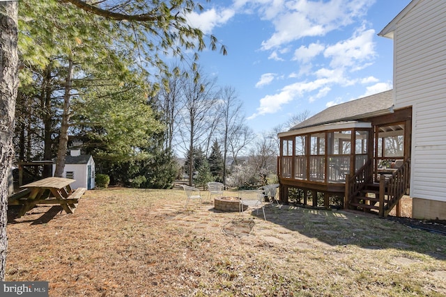 view of yard featuring a shed, a fire pit, and a sunroom