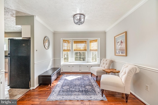 sitting room featuring crown molding, hardwood / wood-style flooring, and a textured ceiling