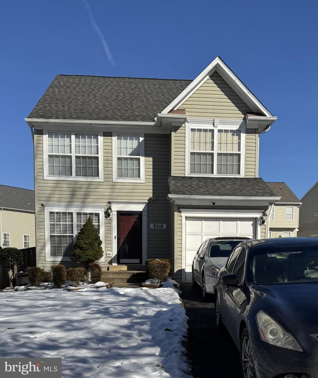 traditional home with a garage and a shingled roof