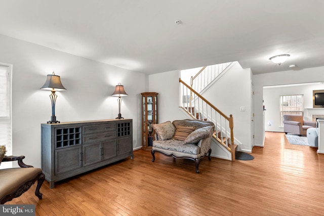 sitting room with light wood finished floors, stairway, and a fireplace