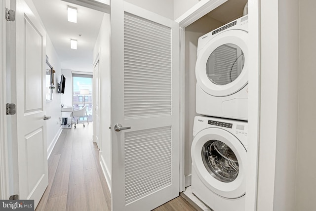 laundry area with stacked washer / dryer and hardwood / wood-style floors