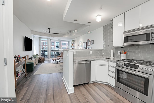 kitchen with white cabinetry, appliances with stainless steel finishes, sink, and kitchen peninsula