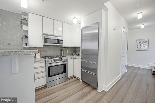 kitchen featuring appliances with stainless steel finishes, light wood-type flooring, decorative backsplash, and white cabinets