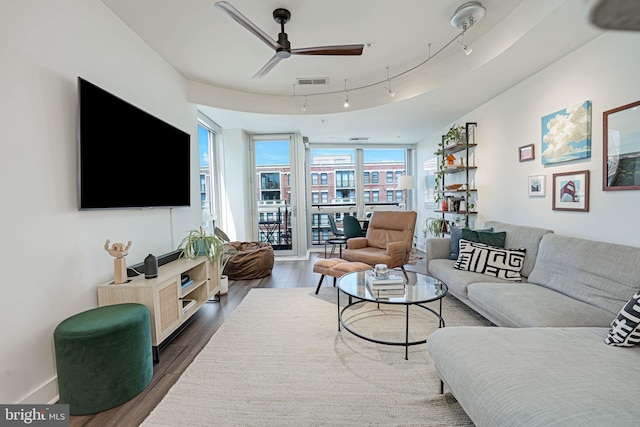 living room featuring dark hardwood / wood-style flooring, ceiling fan, rail lighting, and expansive windows