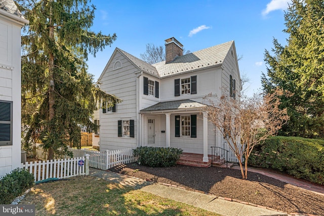 view of front of house with a porch, fence, and a chimney