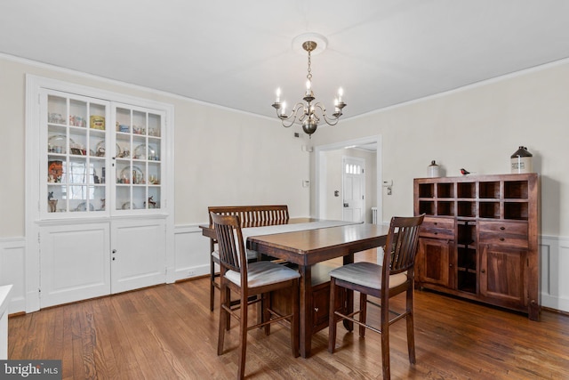 dining space with a wainscoted wall, crown molding, a decorative wall, and wood finished floors