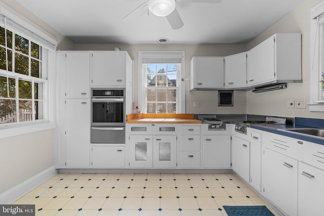 kitchen with visible vents, stainless steel oven, white cabinetry, a warming drawer, and light floors