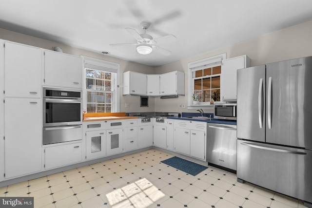 kitchen with stainless steel appliances, white cabinetry, a warming drawer, and light floors