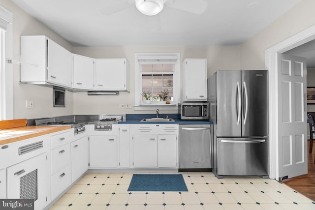 kitchen with white cabinets, light floors, stainless steel appliances, and a sink