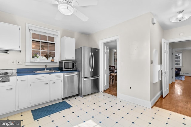 kitchen featuring light floors, a baseboard heating unit, stainless steel appliances, and a sink