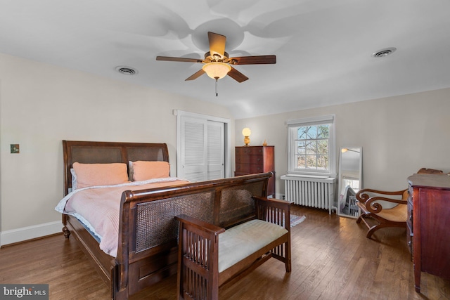 bedroom with radiator, visible vents, baseboards, and hardwood / wood-style floors