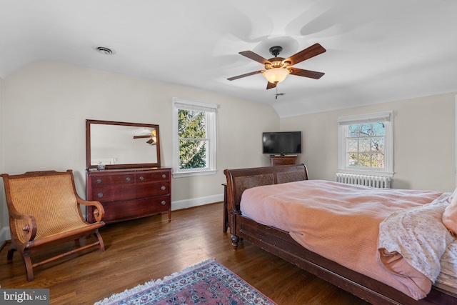 bedroom with baseboards, visible vents, radiator heating unit, wood finished floors, and vaulted ceiling