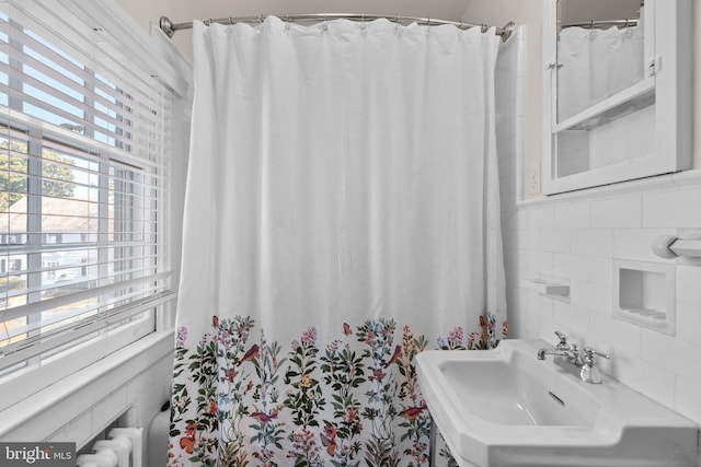 bathroom with tasteful backsplash, a sink, and tile walls