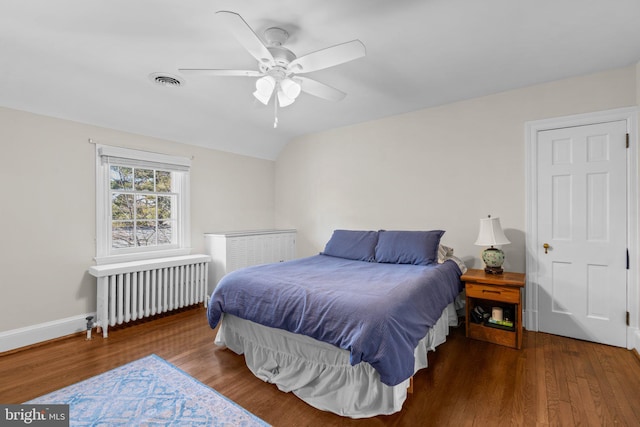 bedroom with radiator, visible vents, wood finished floors, and lofted ceiling