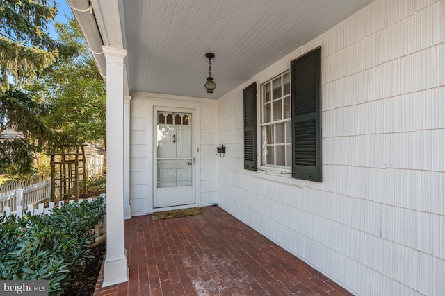 property entrance featuring a porch and fence