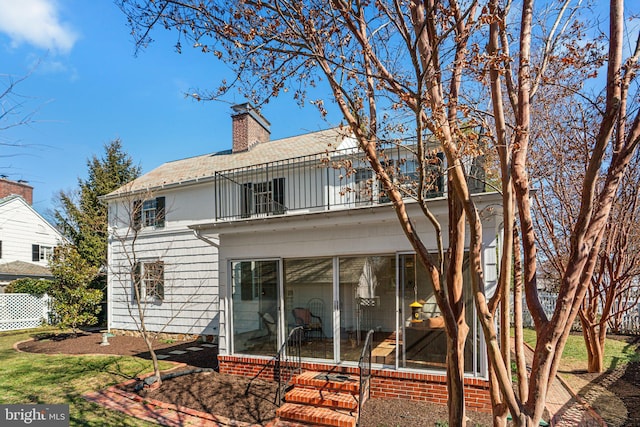 rear view of property featuring a sunroom, a chimney, fence, and a balcony