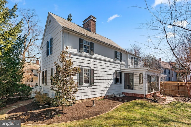 rear view of house featuring a yard, fence, and a chimney