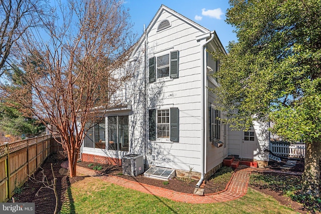 back of house with a yard, central AC unit, entry steps, a sunroom, and fence