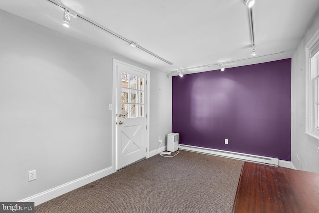 carpeted empty room with a baseboard heating unit, baseboards, and track lighting