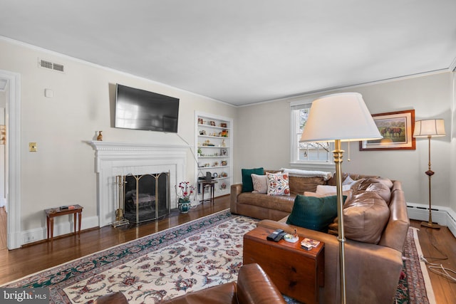 living area featuring a fireplace, wood finished floors, visible vents, built in features, and crown molding