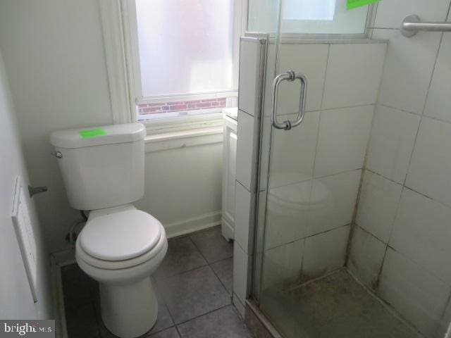 bathroom featuring walk in shower, toilet, and tile patterned flooring