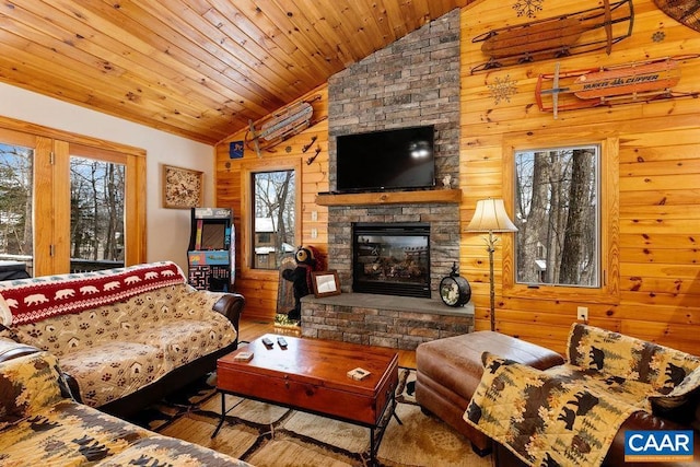 living room with wooden ceiling, a stone fireplace, vaulted ceiling, and wood walls