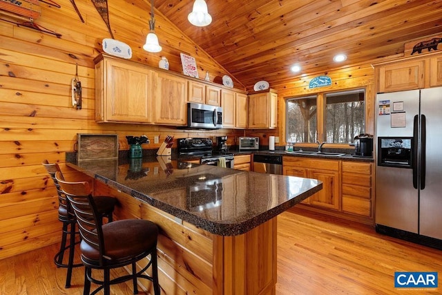 kitchen with sink, a breakfast bar area, stainless steel appliances, kitchen peninsula, and light wood-type flooring