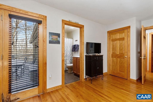 bedroom with connected bathroom and light hardwood / wood-style flooring