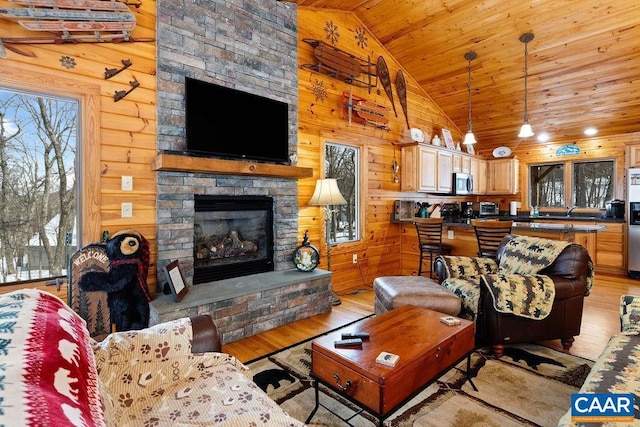 living room featuring lofted ceiling, a stone fireplace, light hardwood / wood-style flooring, wooden ceiling, and wooden walls