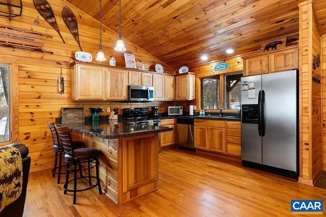 kitchen with pendant lighting, lofted ceiling, a breakfast bar area, stainless steel appliances, and light hardwood / wood-style flooring