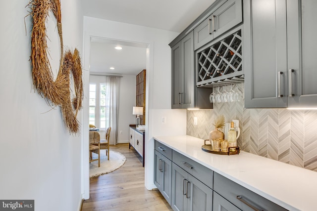 kitchen with tasteful backsplash, gray cabinets, and light hardwood / wood-style flooring