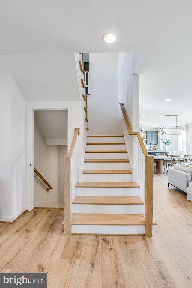 staircase with hardwood / wood-style flooring and a chandelier