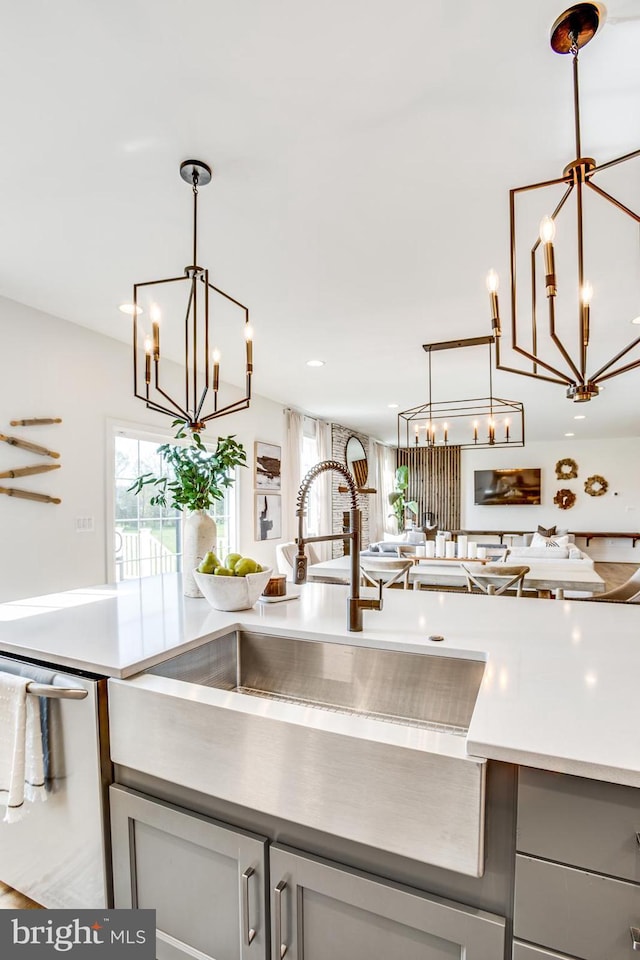 kitchen featuring hanging light fixtures, gray cabinetry, stainless steel dishwasher, and a notable chandelier