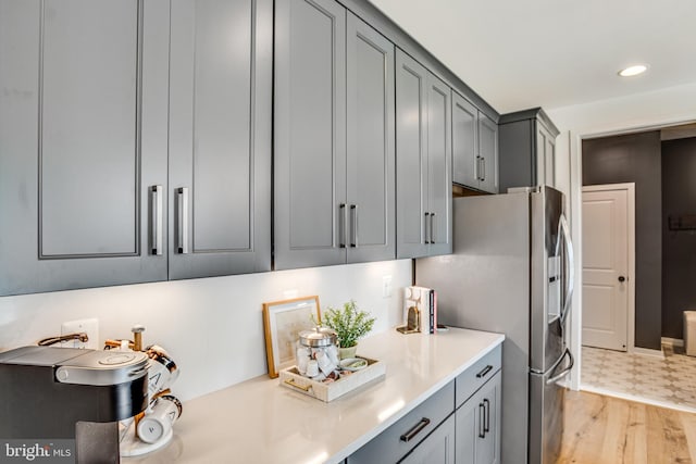 kitchen with gray cabinetry, stainless steel fridge with ice dispenser, and light hardwood / wood-style floors