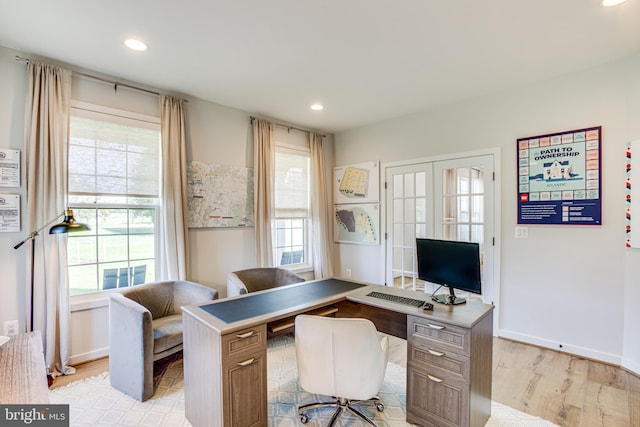 home office featuring french doors, a healthy amount of sunlight, and light wood-type flooring