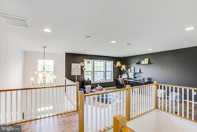 corridor featuring a healthy amount of sunlight, hardwood / wood-style floors, and a chandelier