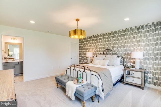 bedroom featuring light carpet, sink, and ensuite bathroom