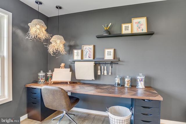 home office with wood-type flooring and an inviting chandelier