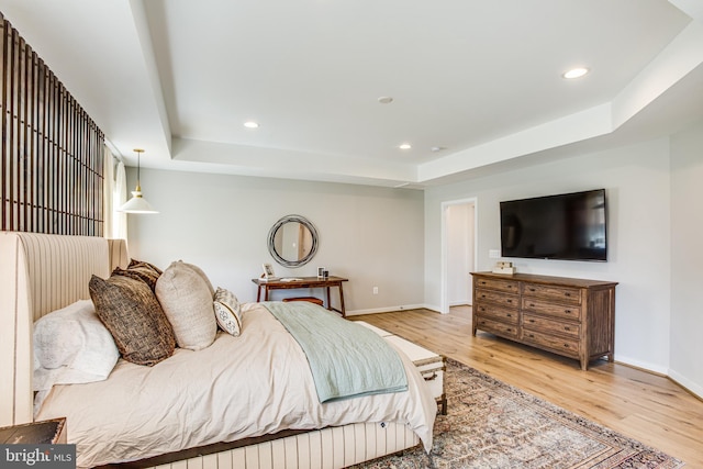 bedroom with a raised ceiling and light hardwood / wood-style flooring
