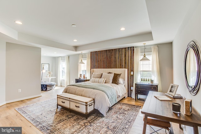 bedroom featuring a raised ceiling and light hardwood / wood-style flooring