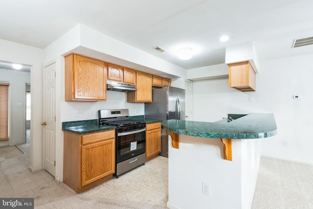 kitchen featuring a breakfast bar area, light colored carpet, and appliances with stainless steel finishes