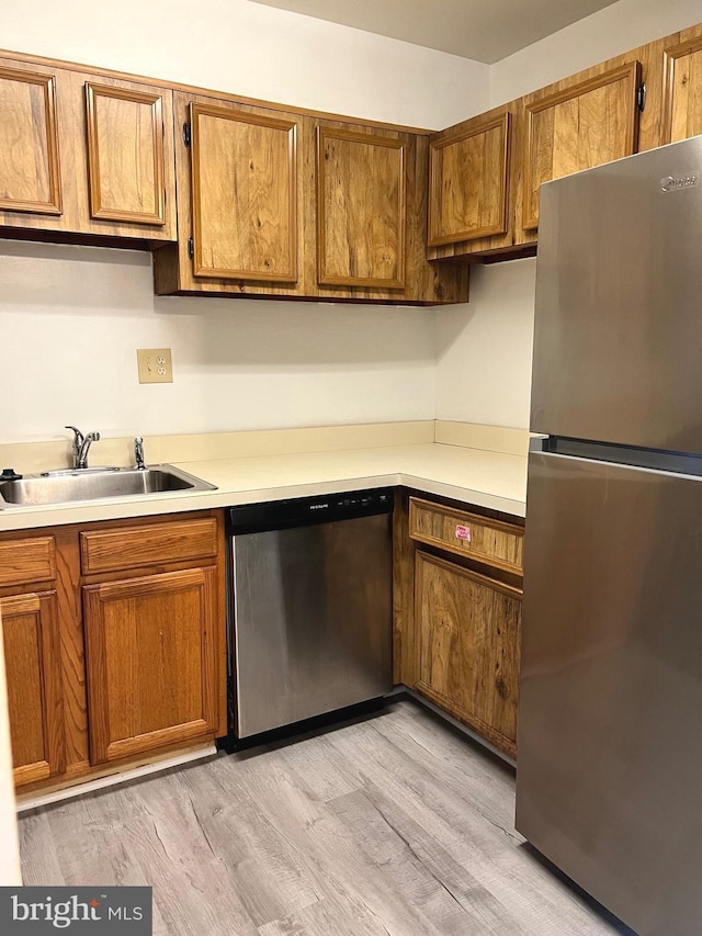 kitchen featuring stainless steel appliances, sink, and light hardwood / wood-style flooring