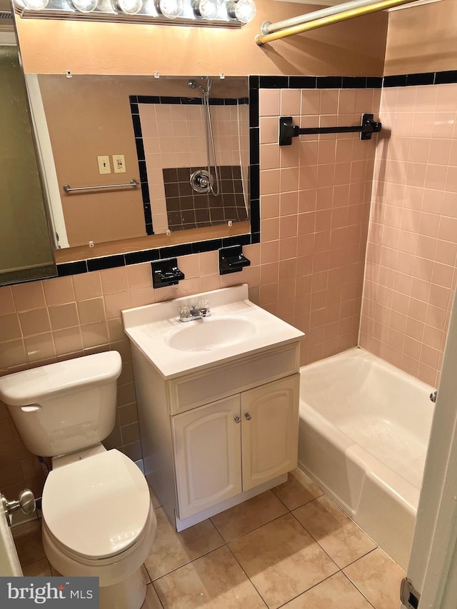 full bathroom with toilet, tiled shower / bath, tile walls, vanity, and tile patterned flooring