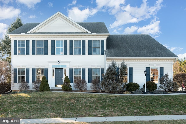 colonial-style house featuring a front yard