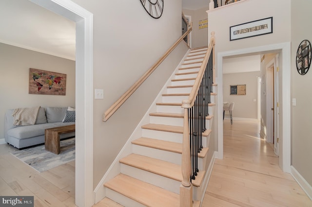 stairs featuring hardwood / wood-style flooring and crown molding