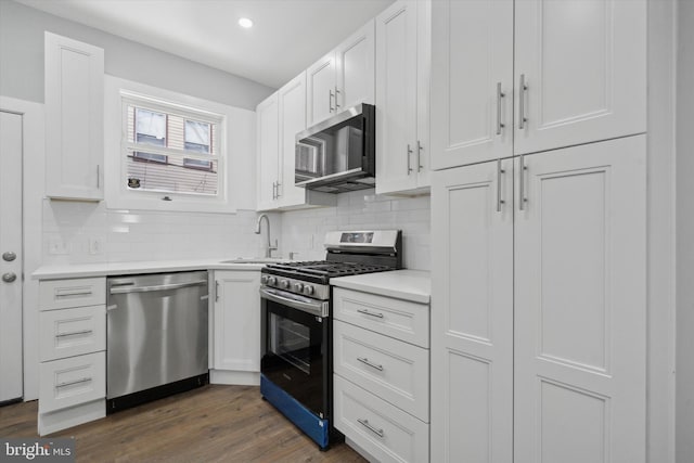 kitchen with tasteful backsplash, appliances with stainless steel finishes, dark wood-type flooring, and white cabinets