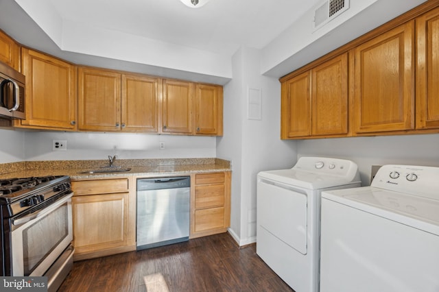 clothes washing area with sink, dark wood-type flooring, and washer and clothes dryer