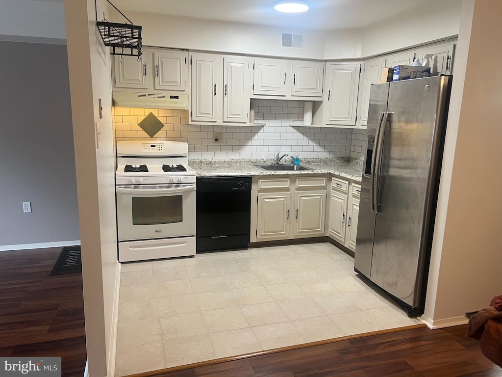 kitchen with sink, stainless steel fridge, white gas range oven, black dishwasher, and white cabinets